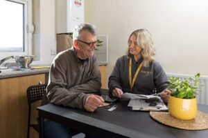 Older couple sitting on a sofa looking at a tablet together and smiling.